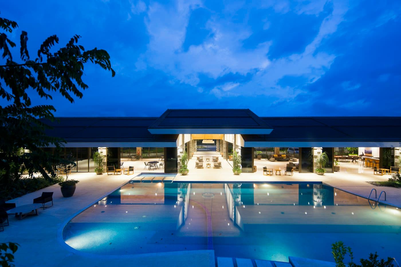 A resort hotel at dusk, its pool lit up in front of the main building